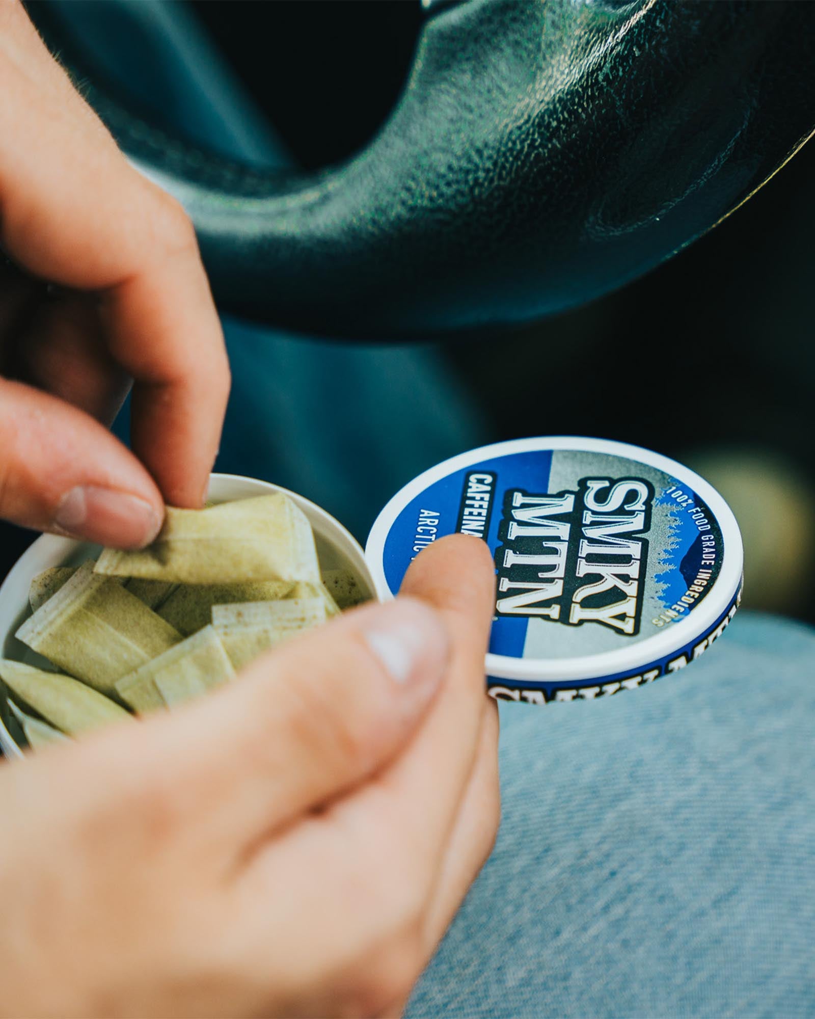 A hand pulling a smokey mountain caffeinated pouch out of a can.